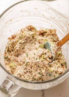 a glass bowl filled with food and a wooden spoon