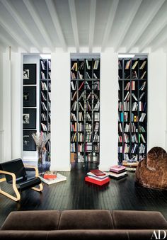 a living room filled with lots of books on top of a hard wood floor covered in furniture