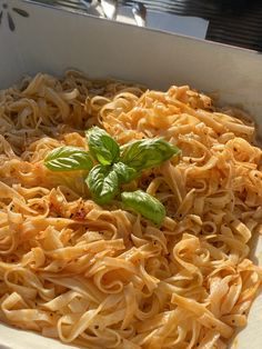 a white box filled with pasta and basil