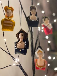 some ornaments are hanging from a tree in the shape of women's heads and dresses