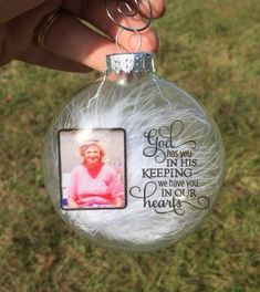 a hand holding a glass ornament with a photo on it