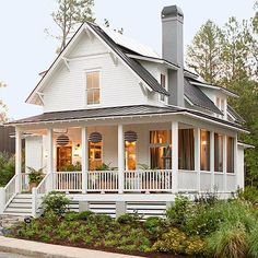 a white house with porches and balconies on the front, surrounded by greenery