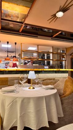 a table with two wine glasses on it in front of a restaurant counter and chefs behind the counter