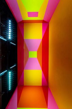 an empty room with neon colored walls and lights on the ceiling is seen in this image