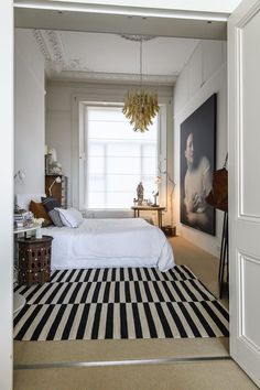 a bedroom with a black and white striped rug on the floor next to a bed