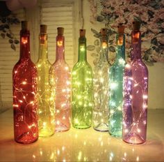 four bottles with lights in them sitting on a table