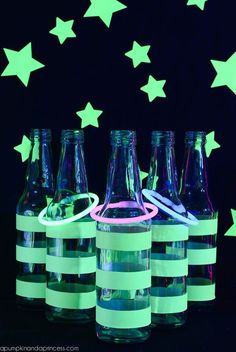 glow in the dark bottles are lined up with neon green and white striped paper strips