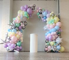 balloons and stars are arranged in the shape of an o - letter on a wall