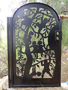 a metal gate with people and trees cut into it