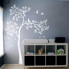 a baby's room with a tree painted on the wall