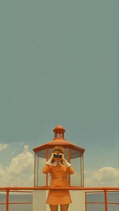 a woman standing on top of a boat looking at the ocean with binoculars in her hand