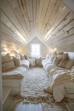 an attic bedroom with lots of pillows and blankets on the bed, along with lights