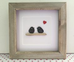 two black birds sitting on top of a wooden shelf next to a red and white heart