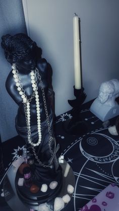 a black statue sitting on top of a table next to a candle and other items