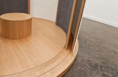 a round wooden object on top of a wood floor next to a wall with mesh coverings