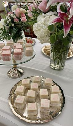 there are many cupcakes on the table with flowers in vases behind them