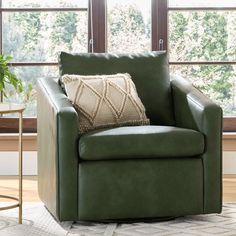 a green chair with a pillow on top of it in front of a large window