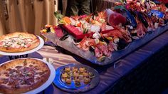 several different types of food are on display at a buffet table with people in the background