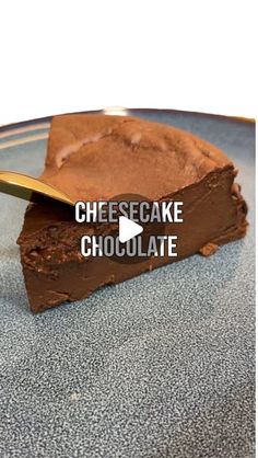 a piece of chocolate cheesecake on a plate with a gold spoon next to it