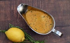 there is a lemon and some herbs on the table next to this pot filled with soup