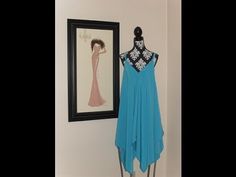 a blue dress hanging on a wall next to a framed drawing and mannequin