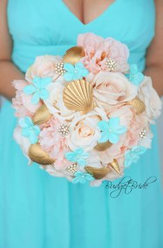 a woman in a blue dress holding a bouquet with flowers and seashells on it