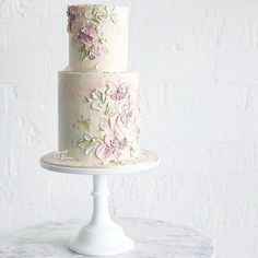 a three tiered wedding cake with pink flowers on the top and white icing