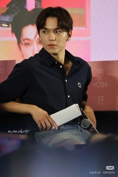 a young man is sitting down and holding a piece of paper