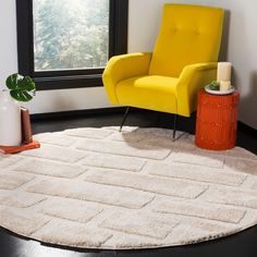 a yellow chair sitting on top of a rug in a living room next to a window