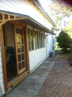 an outside view of a white house with wood trimmings and brick walkway leading up to the front door