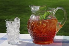 a pitcher filled with liquid sitting on top of a table next to ice cubes