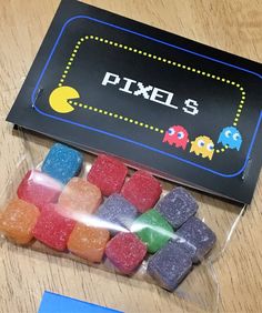 there is a bag of gummy bears in front of the box that says pixels