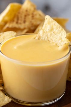 a glass bowl filled with cheese dip and chips