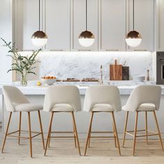 a kitchen with marble counter tops and white chairs in front of an island that has gold pendant lights hanging from the ceiling