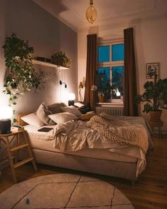 a bed room with a neatly made bed next to a window and potted plants