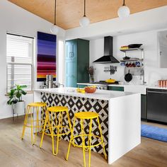 a kitchen with yellow stools and an island in the middle, surrounded by white walls