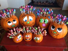 several pumpkins with faces painted on them sitting on a table next to candy sticks