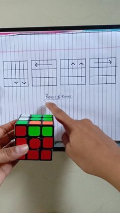 someone is holding a rubik cube in front of a sheet of paper with numbers on it