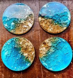 four blue and gold plates sitting on top of a wooden table