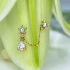 a pair of earrings sitting on top of a green flower next to a white lily