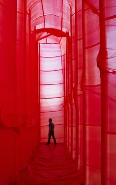 a person standing in the middle of a red tunnel