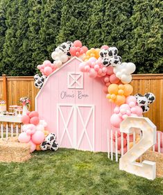 a pink barn decorated with balloons and farm animals for an outdoor birthday party or baby shower