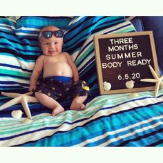 a baby sitting on top of a bed next to a sign that says three months summer body ready