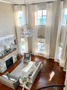 an aerial view of a living room with couches, fireplace and chandelier