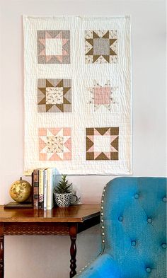 a blue chair sitting in front of a wooden table next to a wall hanging on the wall