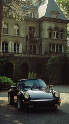 a black sports car parked in front of a large house