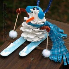 a snowman made out of toothpicks on top of a wooden table with blue and white decorations