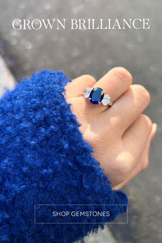 a woman's hand wearing a blue ring with two diamonds on it and the words crown