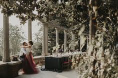 a man and woman standing next to each other under trees