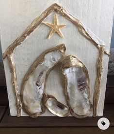 three seashells in front of a white wooden frame with a star on top